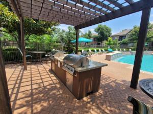 Apartments in Jersey Village, TX - Outdoor Grilling Area with Seating Under Pergola